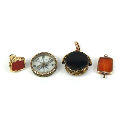 2622 - Three gilt metal hard stone fobs including a spinning locket together with a compass