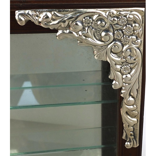 101 - Silver cornered wall hanging display case with glazed door and three glass shelves, the silver corne... 