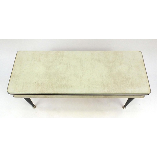 55 - Retro cream leatherette coffee table raised on tapering legs, 48cm high x 107cm wide x 41cm deep