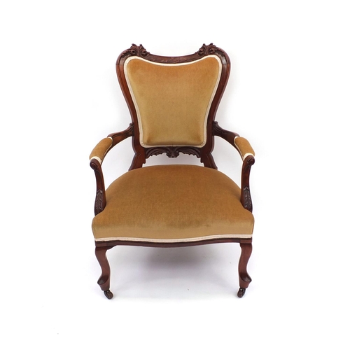 2053 - Carved walnut elbow chair with gold upholstery raised on cabriole legs and china castors, 88cm high