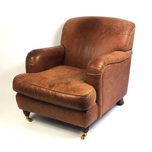 2016 - Brown leather club chair with mahogany feet and brass castors, 86cm high