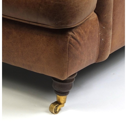 2016 - Brown leather club chair with mahogany feet and brass castors, 86cm high