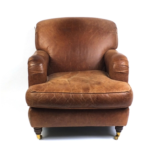 2016 - Brown leather club chair with mahogany feet and brass castors, 86cm high