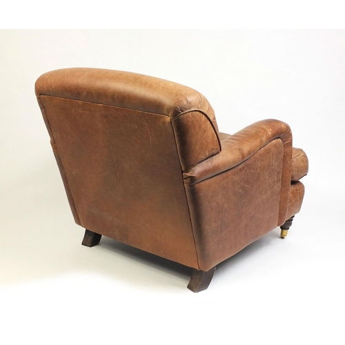 2016 - Brown leather club chair with mahogany feet and brass castors, 86cm high