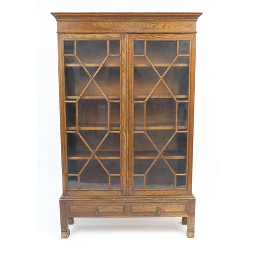 76 - Oak bookcase fitted wit a pair of astragal glazed doors, four adjustable shelves and two drawers to ... 