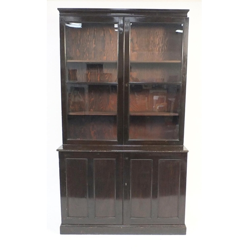 28 - Stained wood book case fitted with a pair of glazed doors, enclosing three shelves above a cupboard ... 