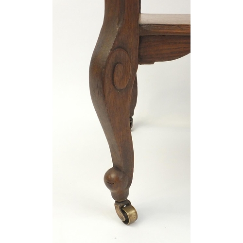 105 - Carved oak occasional table with under tier raised on cabriole legs and castors, 75cm high x 60cm wi... 