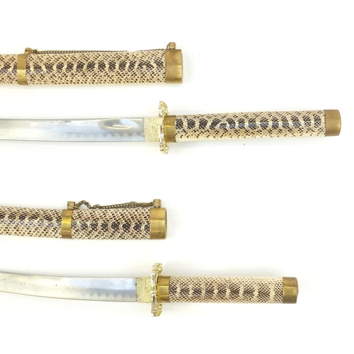 193 - Graduated set of three decorative Japanese Samurai swords with simulated snake skin, the larger 101c... 