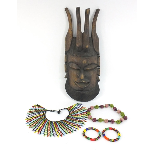 399 - African carved wooden wall mask and a selection of beadwork jewellery