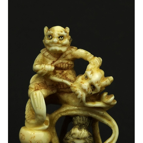 529 - Japanese carved ivory okimono of a Geisha girl standing on a lion, red insect character marks to the... 