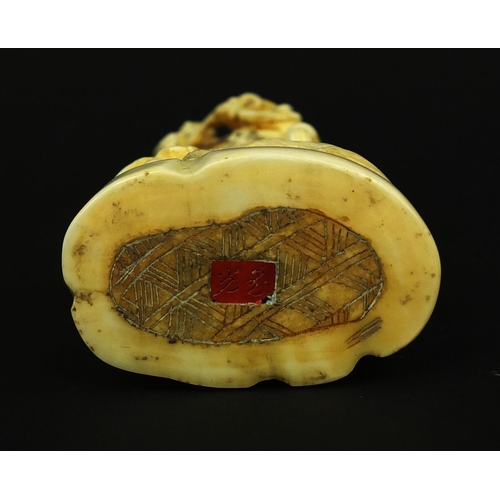 529 - Japanese carved ivory okimono of a Geisha girl standing on a lion, red insect character marks to the... 