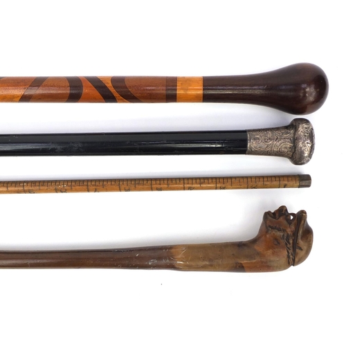 163 - Four wooden walking sticks including an ebonised silver topped example, one carved with a face and a... 