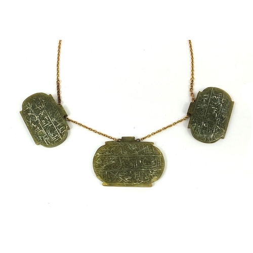 607 - Three Islamic green nephrite panels on a gold coloured metal necklace, the panels carved with script... 