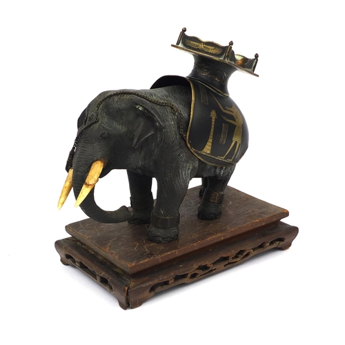 555 - Japanese bronze elephant with ivory tusks and Egyptian design seat, raised on a hardwood base, the e... 