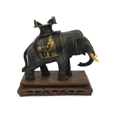 555 - Japanese bronze elephant with ivory tusks and Egyptian design seat, raised on a hardwood base, the e... 