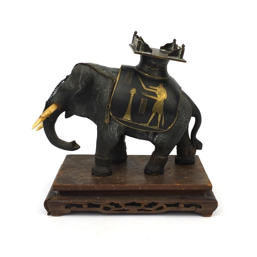 555 - Japanese bronze elephant with ivory tusks and Egyptian design seat, raised on a hardwood base, the e... 