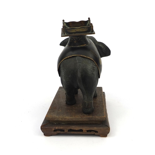 555 - Japanese bronze elephant with ivory tusks and Egyptian design seat, raised on a hardwood base, the e... 