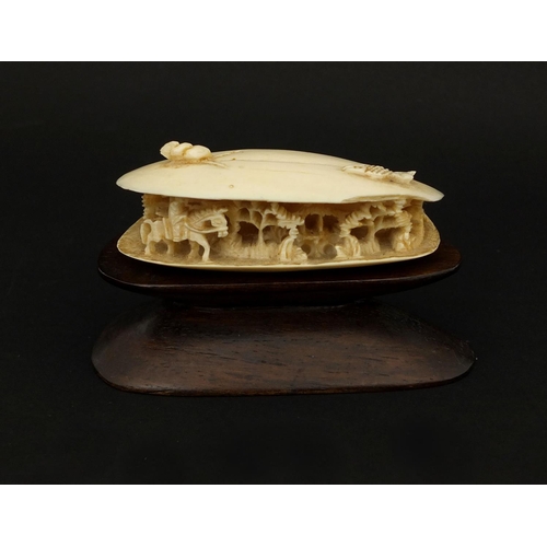 534 - Chinese ivory clam shell, the interior carved with a figure on horseback in a landscape, raised on a... 