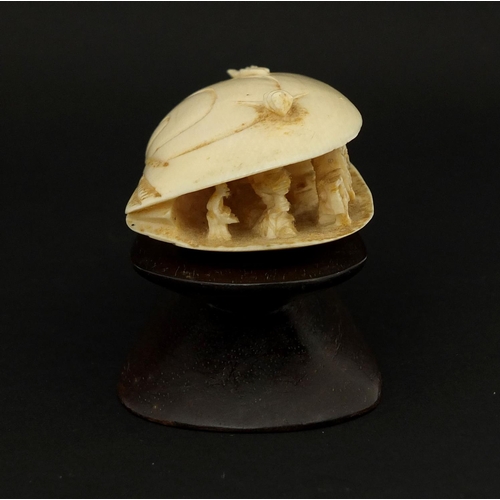 534 - Chinese ivory clam shell, the interior carved with a figure on horseback in a landscape, raised on a... 