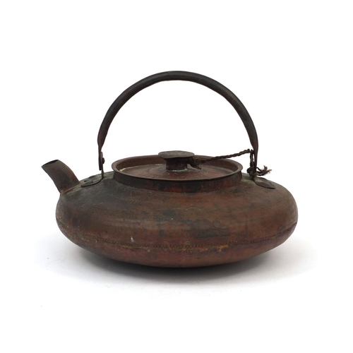 559 - Chinese copper kettle with swinging handle and planished decoration, the body 22cm in diameter