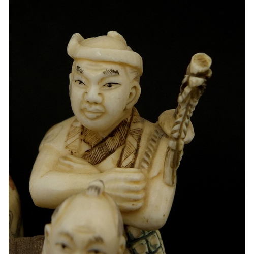 531 - Japanese carved ivory okimono of four figures drinking, character marks to the base, 6cm high