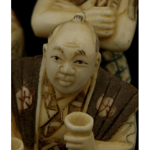 531 - Japanese carved ivory okimono of four figures drinking, character marks to the base, 6cm high