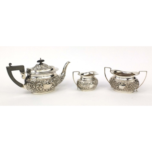 820 - Silver three piece tea service, profusely embossed with flowers, the teapot with ebonised wood handl... 