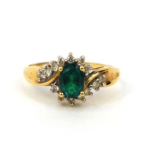 1016 - 18ct gold emerald and diamond crossover ring, set with a central emerald and fourteen diamonds, size... 