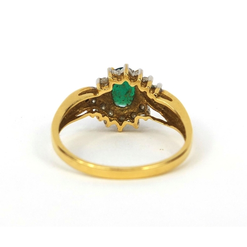 1016 - 18ct gold emerald and diamond crossover ring, set with a central emerald and fourteen diamonds, size... 