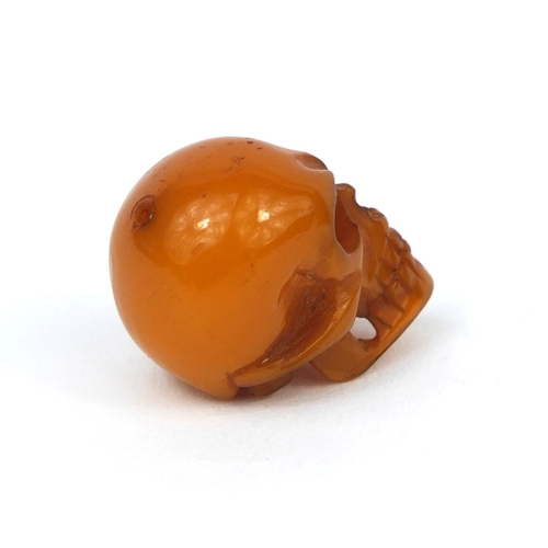 144 - Miniature butterscotch amber coloured carving of a skull, 2.3cm high