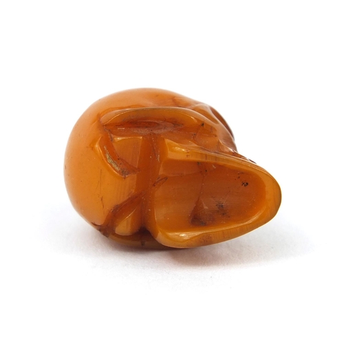 144 - Miniature butterscotch amber coloured carving of a skull, 2.3cm high