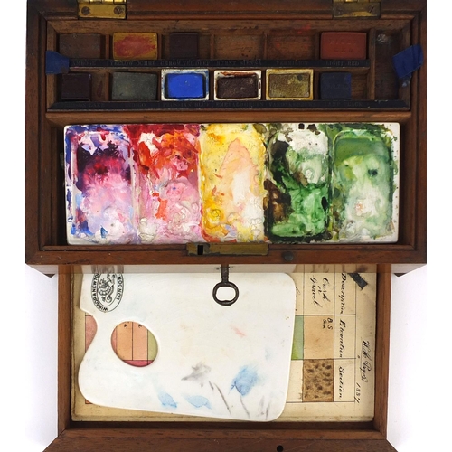 38 - Winsor & Newton Mahogany artists box housing paints and a ceramic palette, 7cm high x 21.5cm wide x ... 