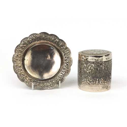 602 - Indian unmarked silver cylindrical box and cover, together with a pin dish, both embossed with flowe... 