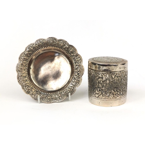 602 - Indian unmarked silver cylindrical box and cover, together with a pin dish, both embossed with flowe... 