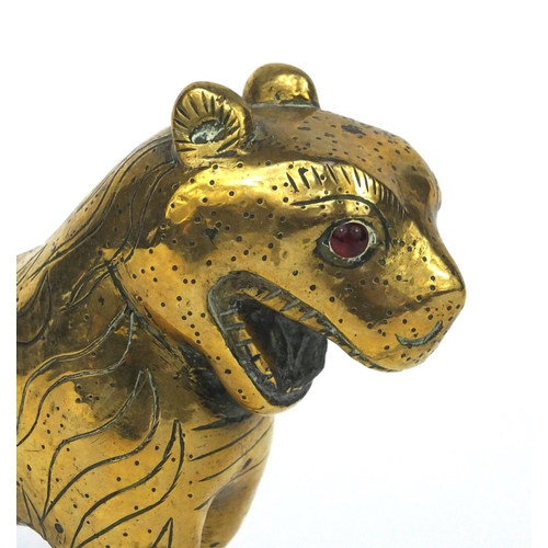 633 - Antique Middle Eastern brass study of a tiger set with a red stone eye, 22cm in length