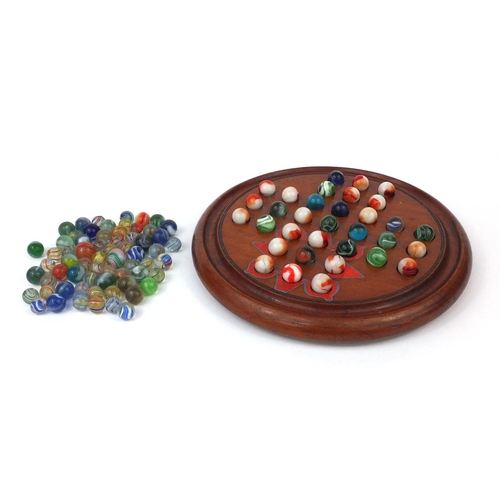 426 - Victorian and later glass marbles, with wooden solitaire board, the solitaire board 26cm in diameter