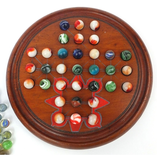 426 - Victorian and later glass marbles, with wooden solitaire board, the solitaire board 26cm in diameter