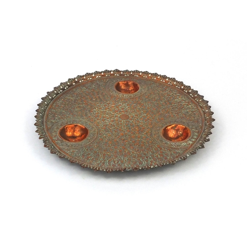 625 - Islamic copper three footed dish, embossed with floral motifs within a pierced border, 27cm diameter