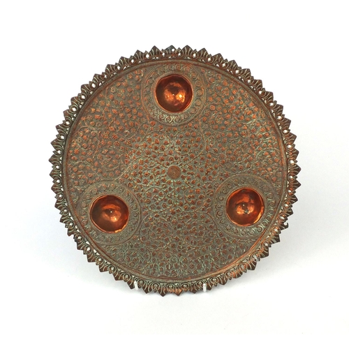 625 - Islamic copper three footed dish, embossed with floral motifs within a pierced border, 27cm diameter