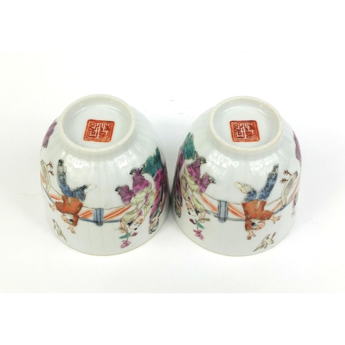 472 - Pair of Chinese porcelain tea cups painted in the famille rose palette with court figures playing, f... 