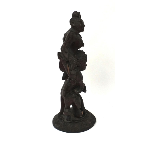 648 - Large Middle Eastern carved wooden figure group of two figures, on a circular base, 77cm high