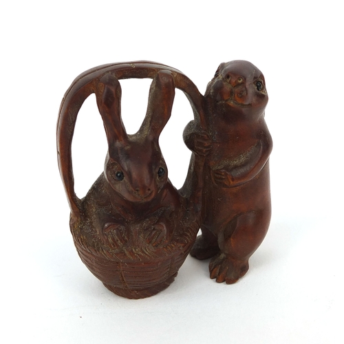 538 - Japanese carved boxwood Netsuke in the form of two rabbits, one in a basket, character to one leg, 5... 