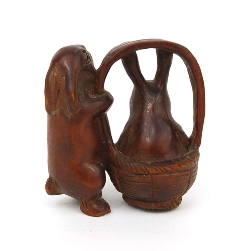 538 - Japanese carved boxwood Netsuke in the form of two rabbits, one in a basket, character to one leg, 5... 