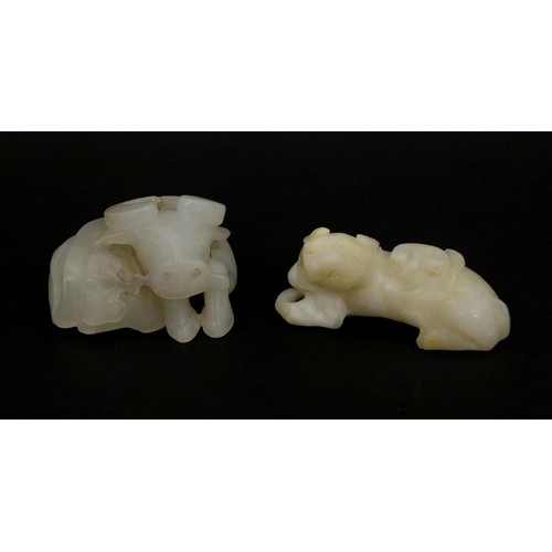 515 - Two Chinese pale jade carvings comprising one of a buffalo biting a branch and one of a dog a foo re... 