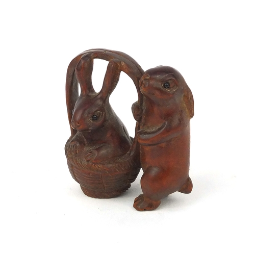 538 - Japanese carved boxwood Netsuke in the form of two rabbits, one in a basket, character to one leg, 5... 