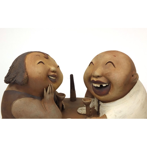 2358 - Two comical Chinese terracotta figure groups  one of two lovers sitting at a dinner table and one of... 