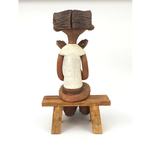 2362 - A comical Chinese terracotta figure seated on a bench, 50cm high