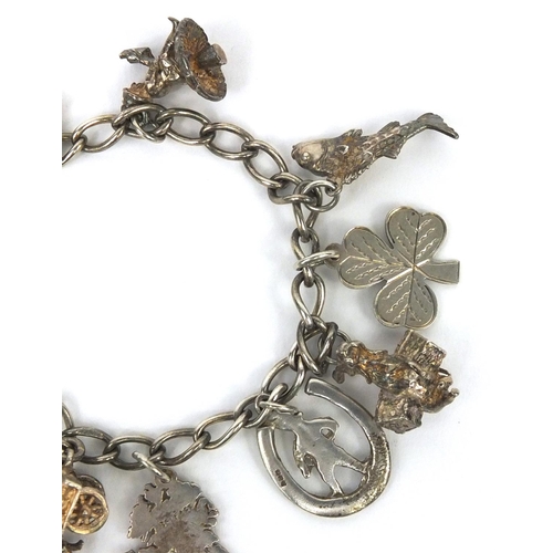 2656 - Silver charm bracelet with selection of mostly silver charms including horse and cart, harp, spinnin... 