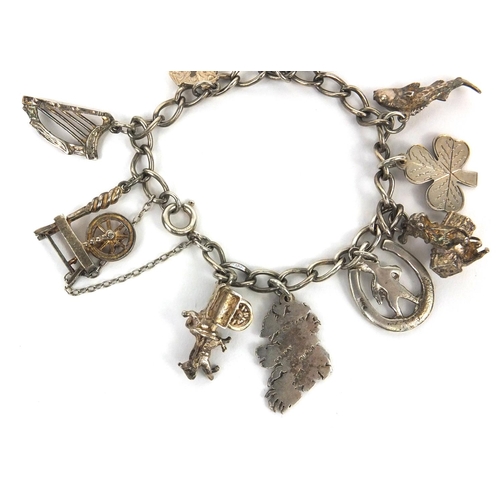 2656 - Silver charm bracelet with selection of mostly silver charms including horse and cart, harp, spinnin... 