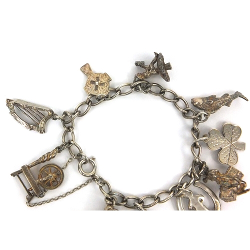 2656 - Silver charm bracelet with selection of mostly silver charms including horse and cart, harp, spinnin... 